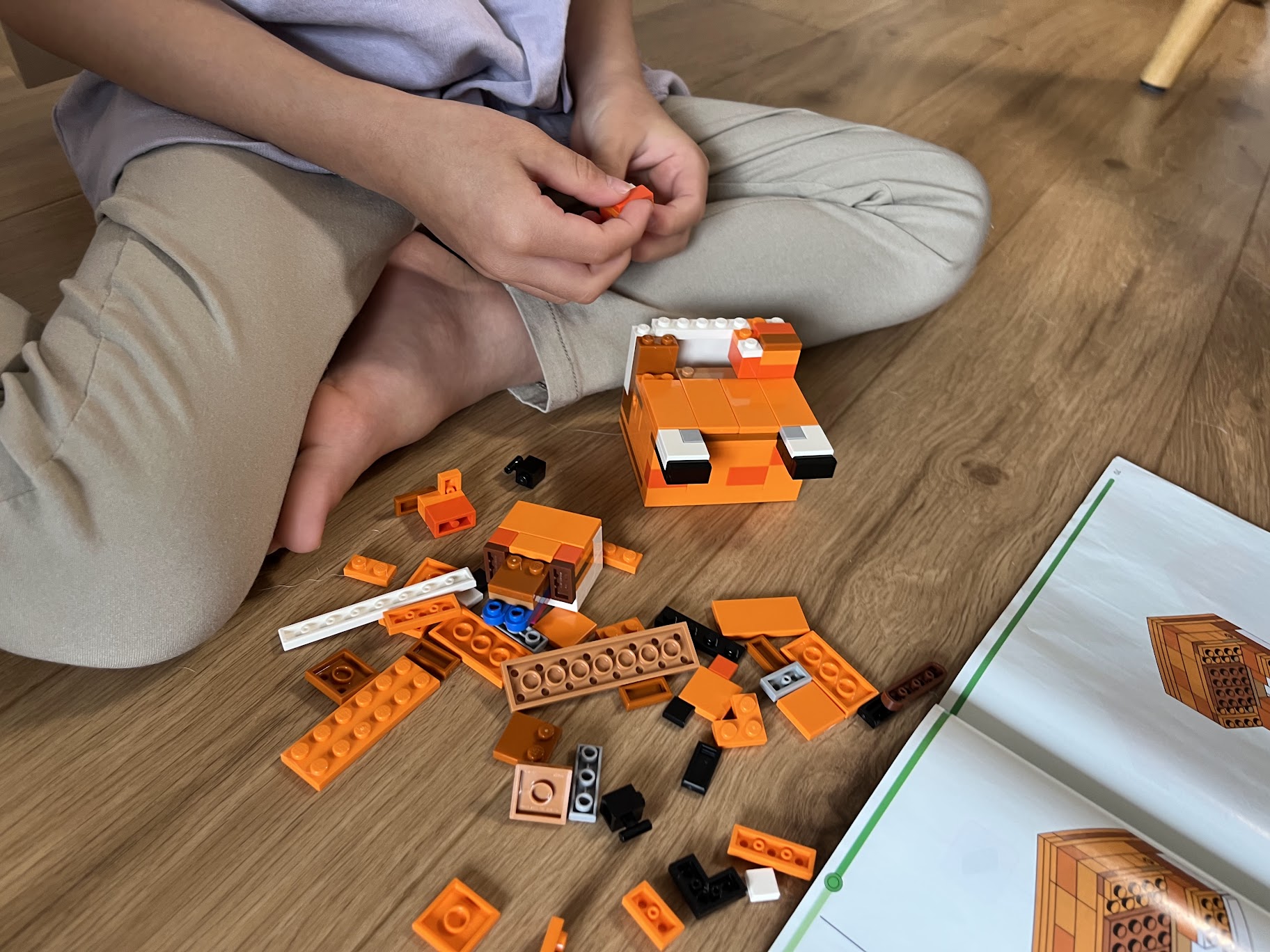 レゴのキツネを説明書を見ながら組み立てる子どもの手元